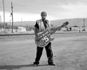 Black and White photograph of a man with a guitar in the desert
